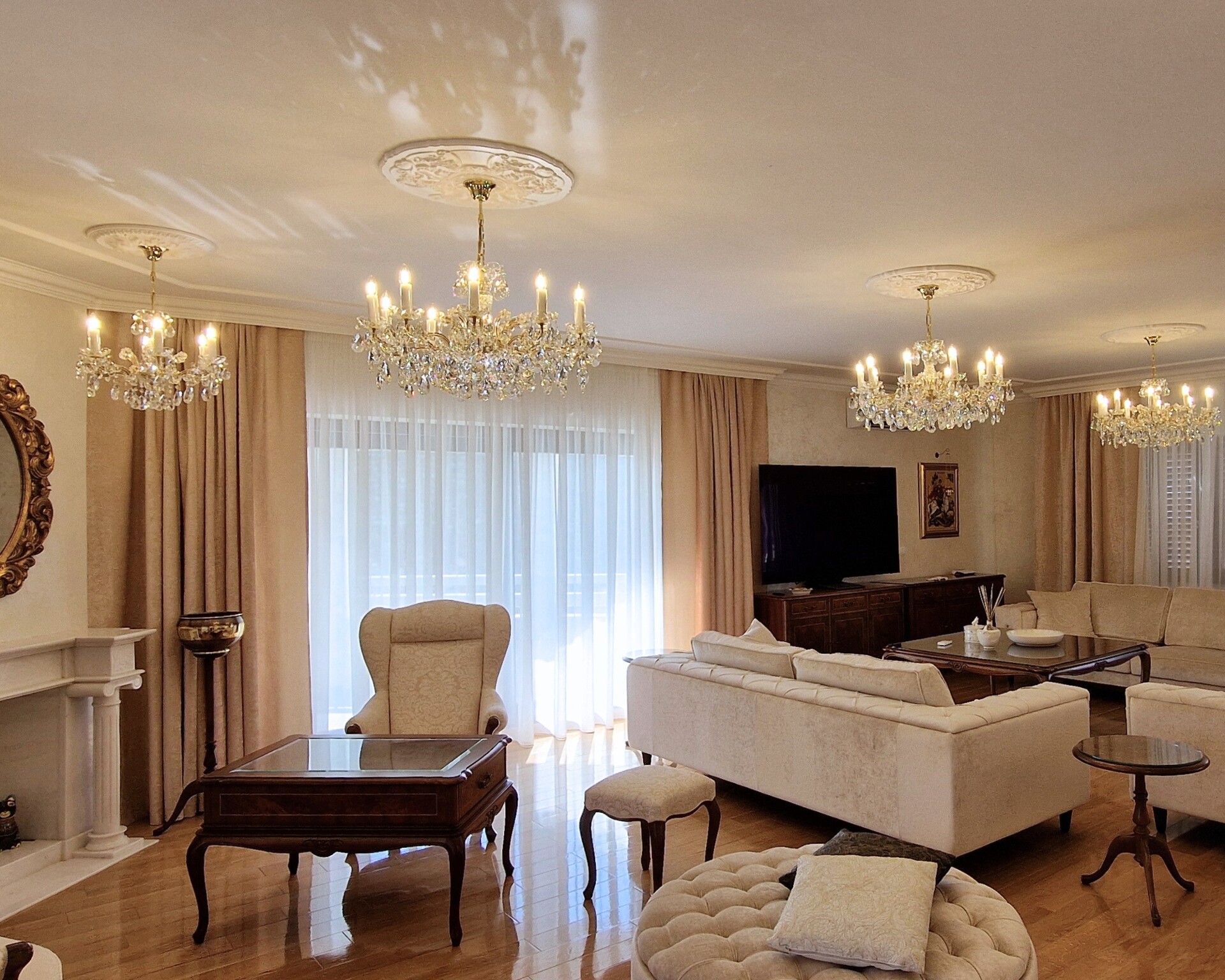 Living room with crystal chandeliers, cream sofas, and a fireplace