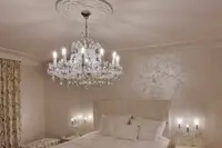 Maria Theresa crystal chandelier in silver finish above the bed in a luxury bedroom with wall sconces