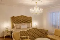 Maria Theresa crystal chandelier in gold finish above a bed with an upholstered headboard in a classic interior