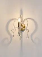 Wall crystal light with one arm and pendants lit up against a white wall