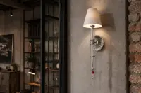 Silver wall lamp in an interior with a brick wall and bookcase