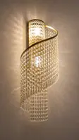 Wall light with a semicircular frame and dense crystal chain pendants lit against a wall