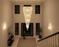 Large spiral crystal chandelier hanging in a tall entrance hall with wall sconces